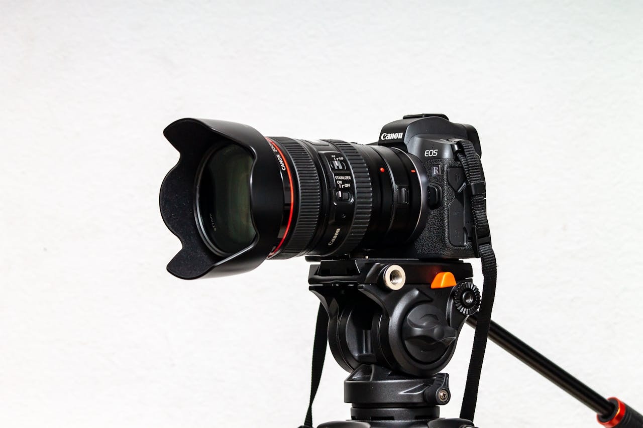 A close-up photo of a black professional camera and an adjustable tripod