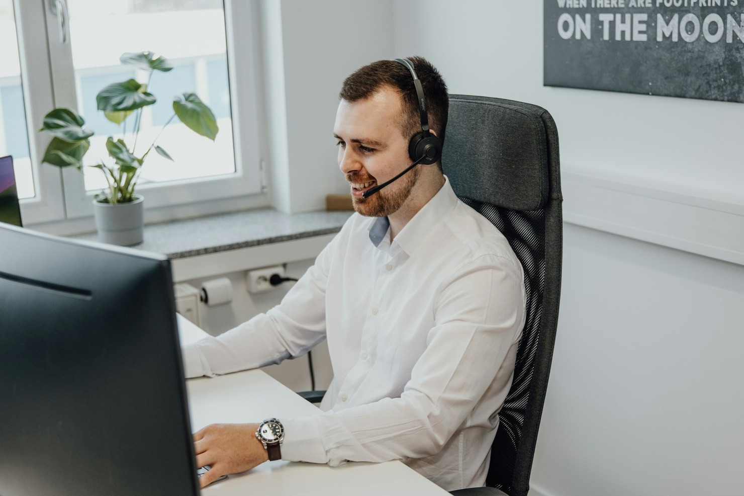 A man wearing a headset in front of the computer