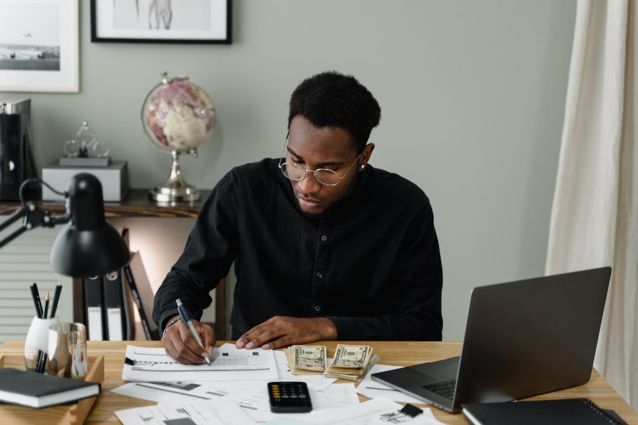 A man working at a desk with a calculator and paper bills