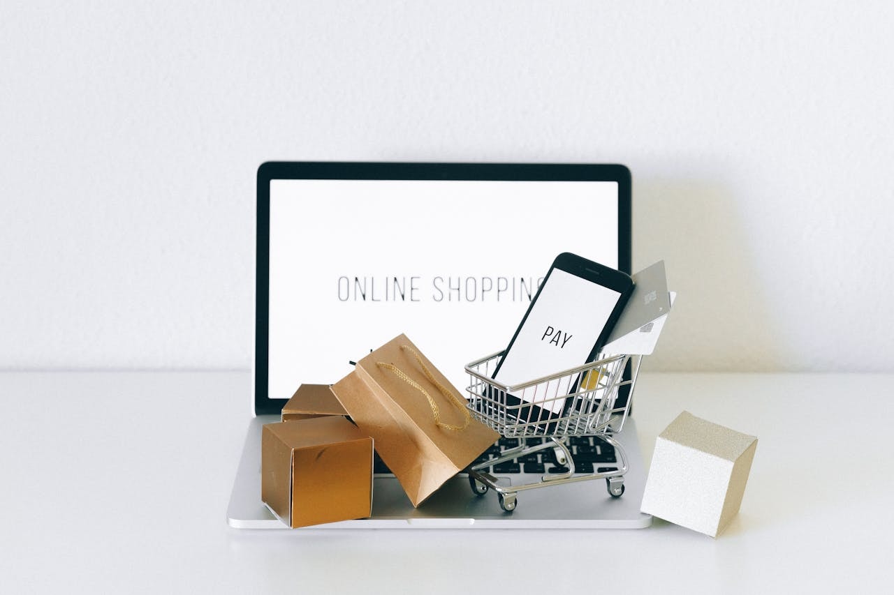 A miniature shopping cart and brown boxes on a laptop