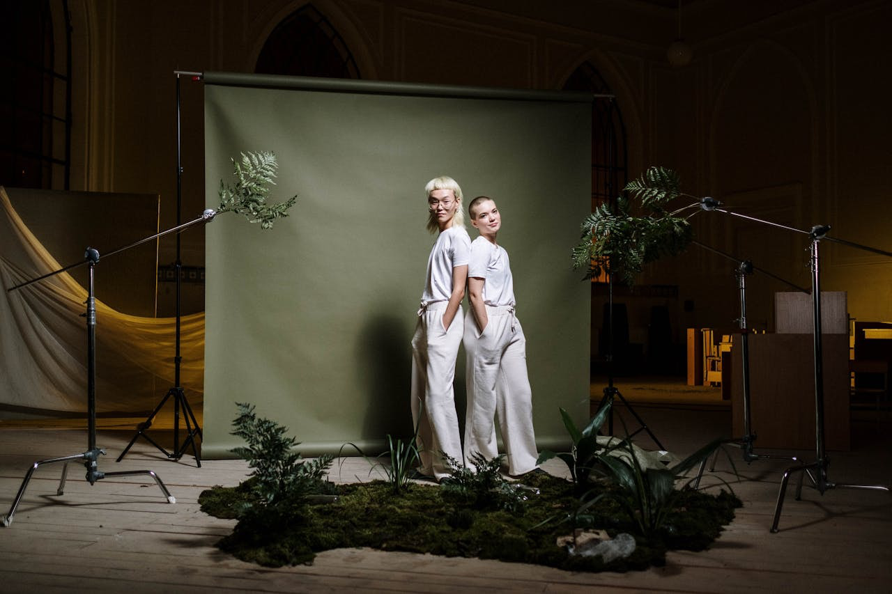 A nature-themed photoshoot setup using a green backdrop in contrast with fashion models in white clothing