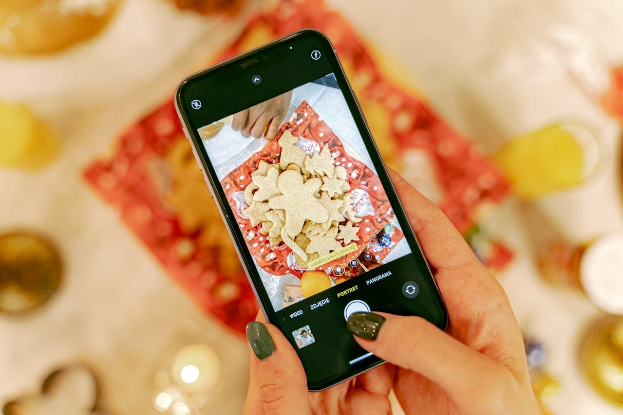 A person taking a photo of cookies using a mobile phone in portrait mode