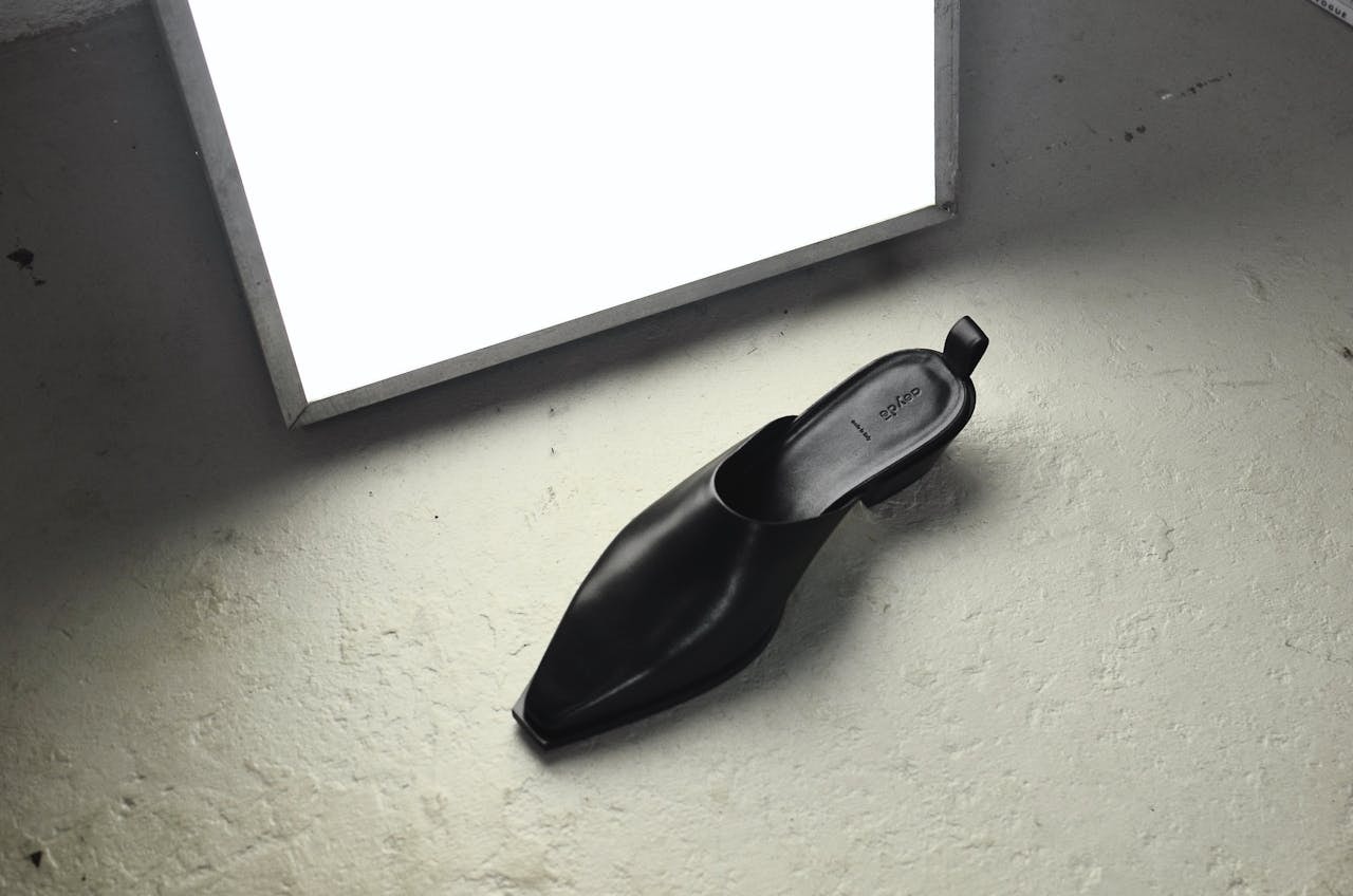 A photo of a black shoe placed near a soft white lamp