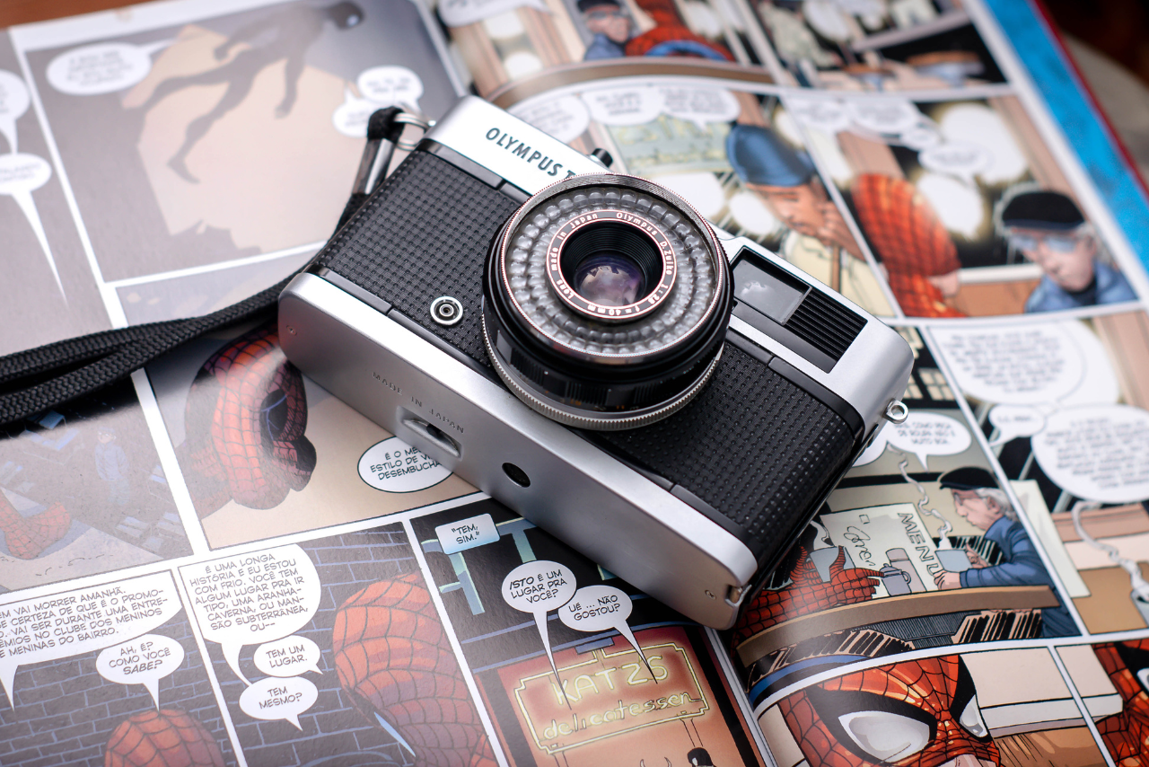 A retro camera sitting on top of an opened comic book.