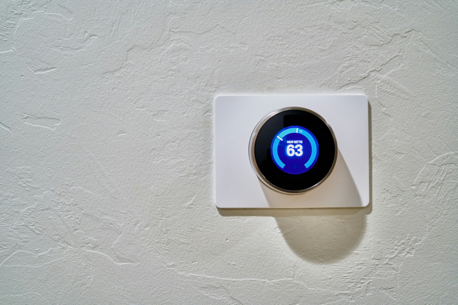 A smart thermostat attached to a white wall