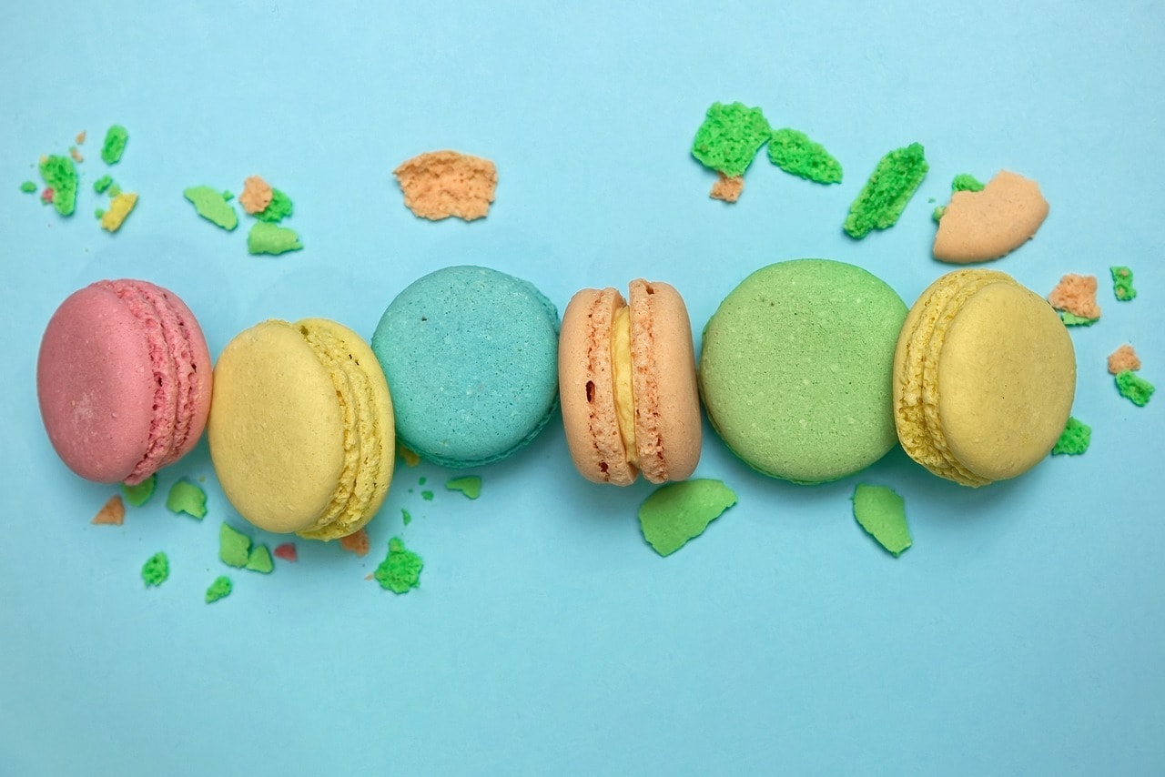 A top-down view of macarons in different colors against a light blue background