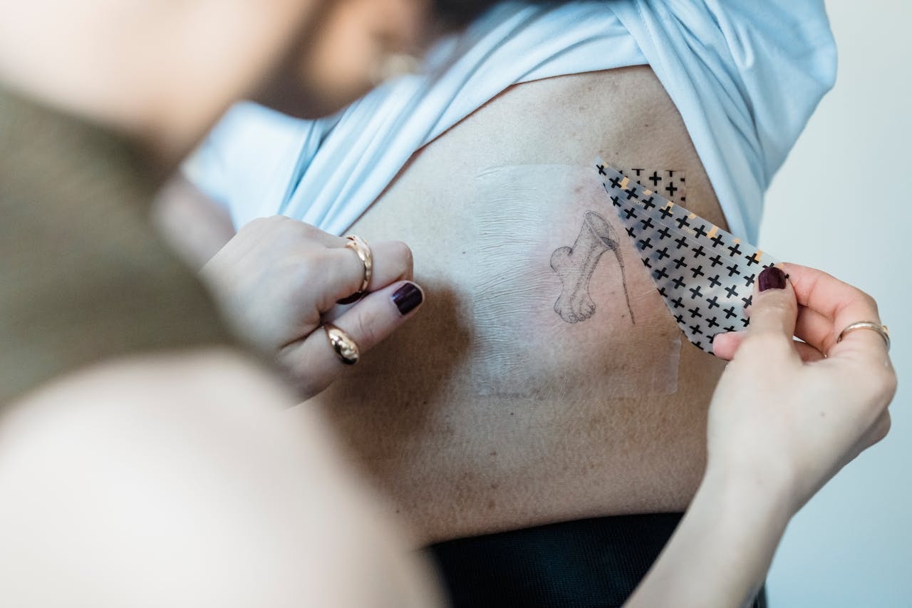 A woman applying a temporary tattoo to a person