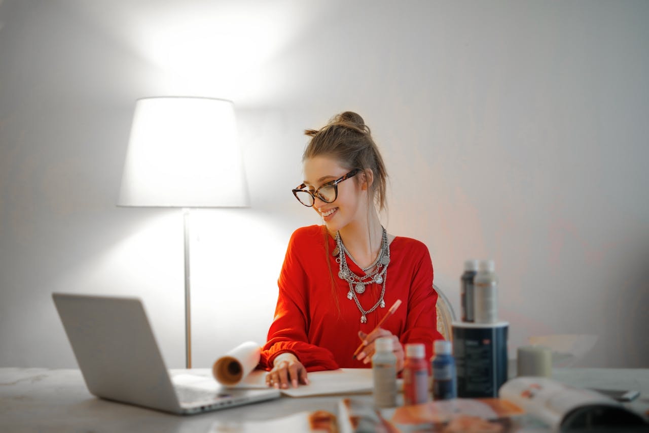 A woman looking at her laptop and taking notes