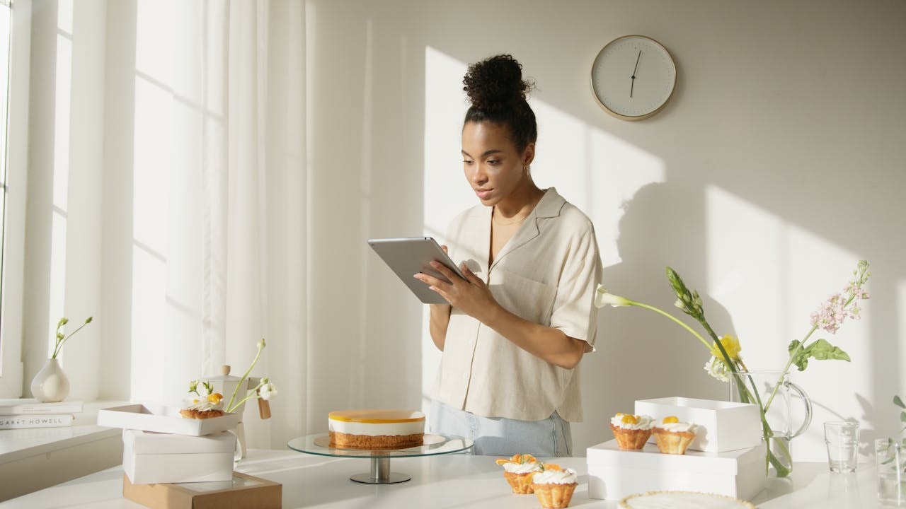A woman selling cakes and looking at a tablet device