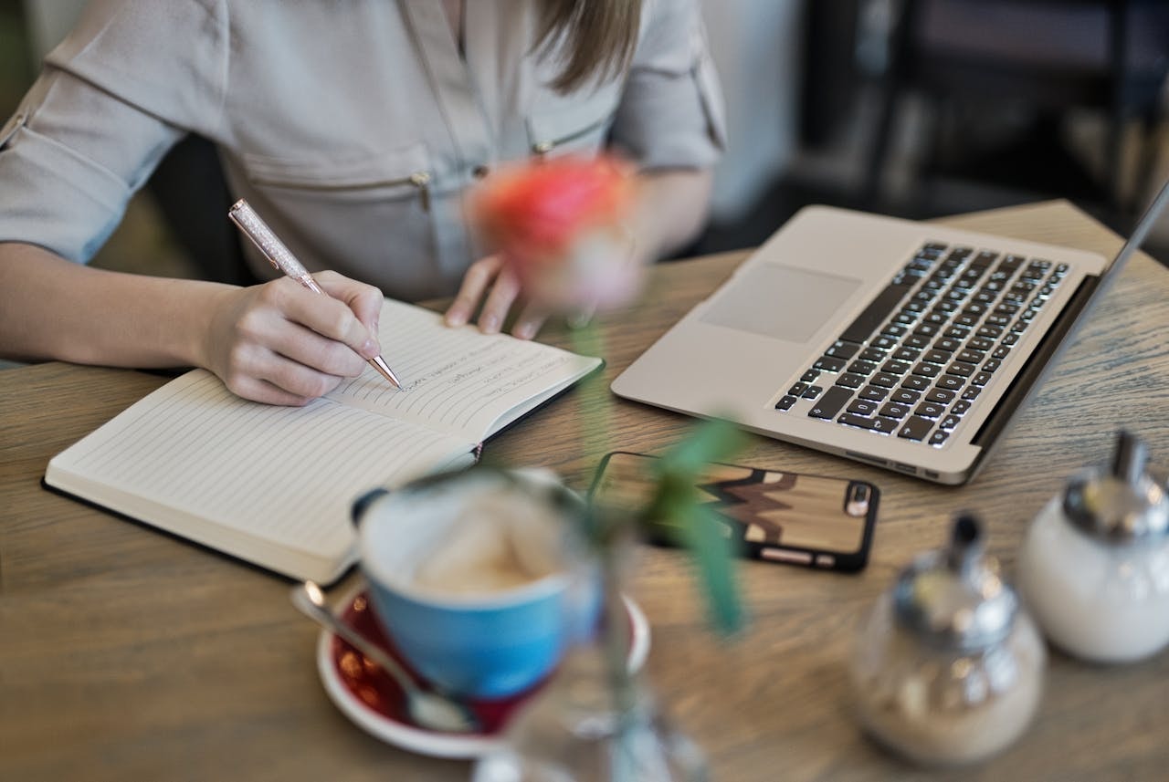 A woman sitting at a table and writing in a notebook