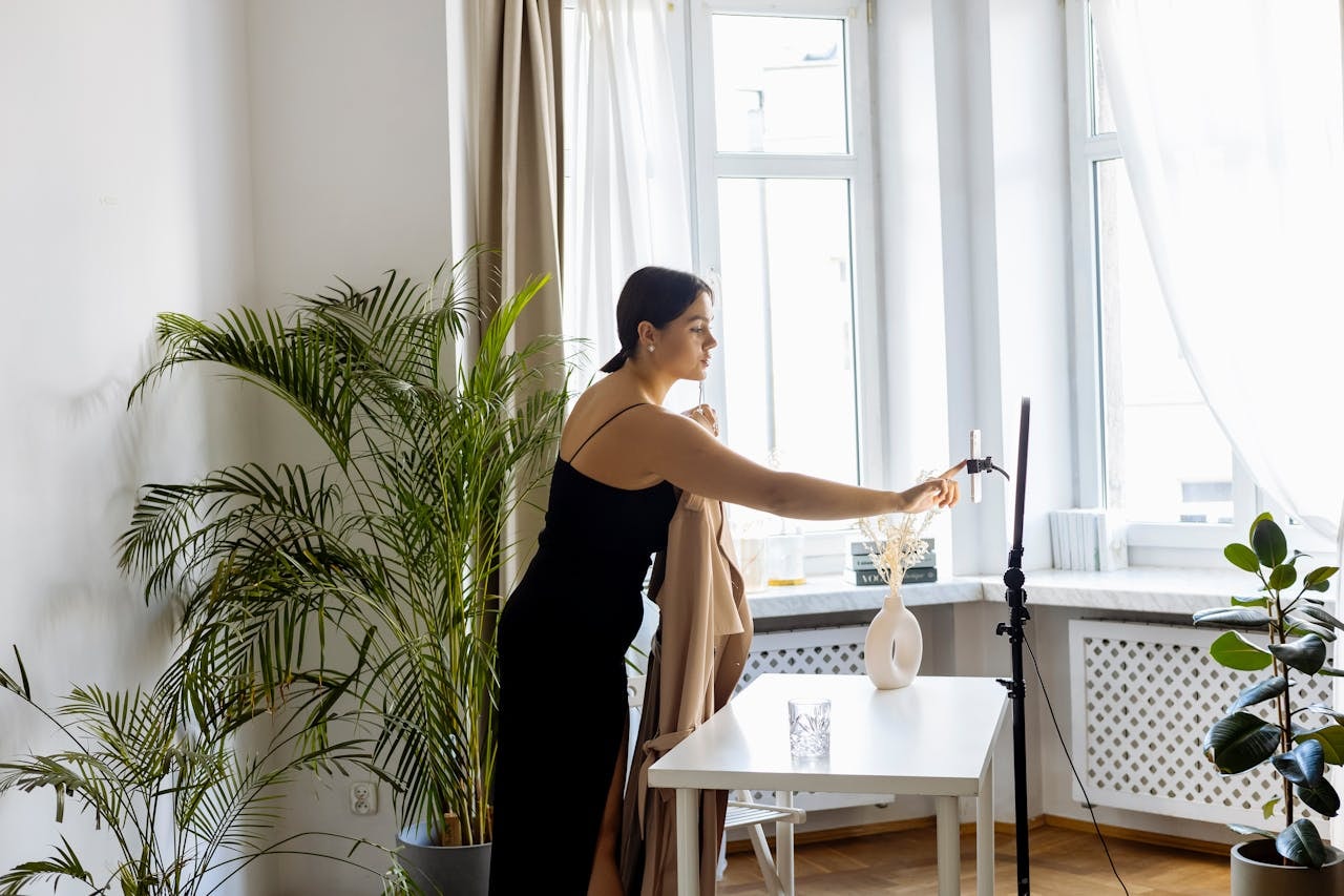 A woman taking a photo of a brown coat using a camera attached to a tripod