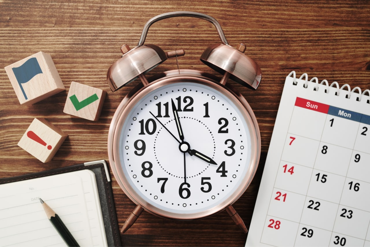 Alarm clock and calendar on wooden table.