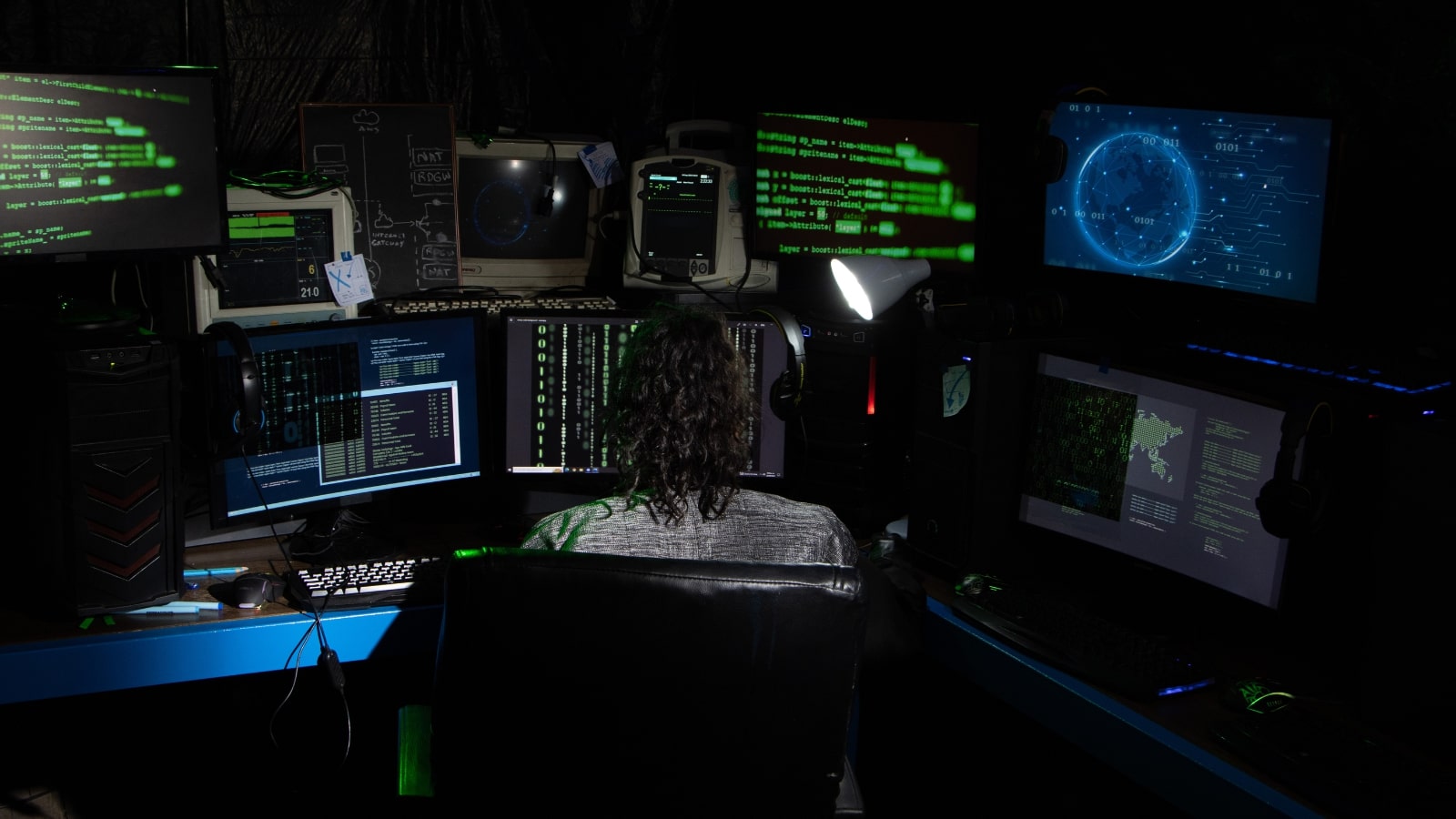 An expert security software developer working infront of multiple computer screens.