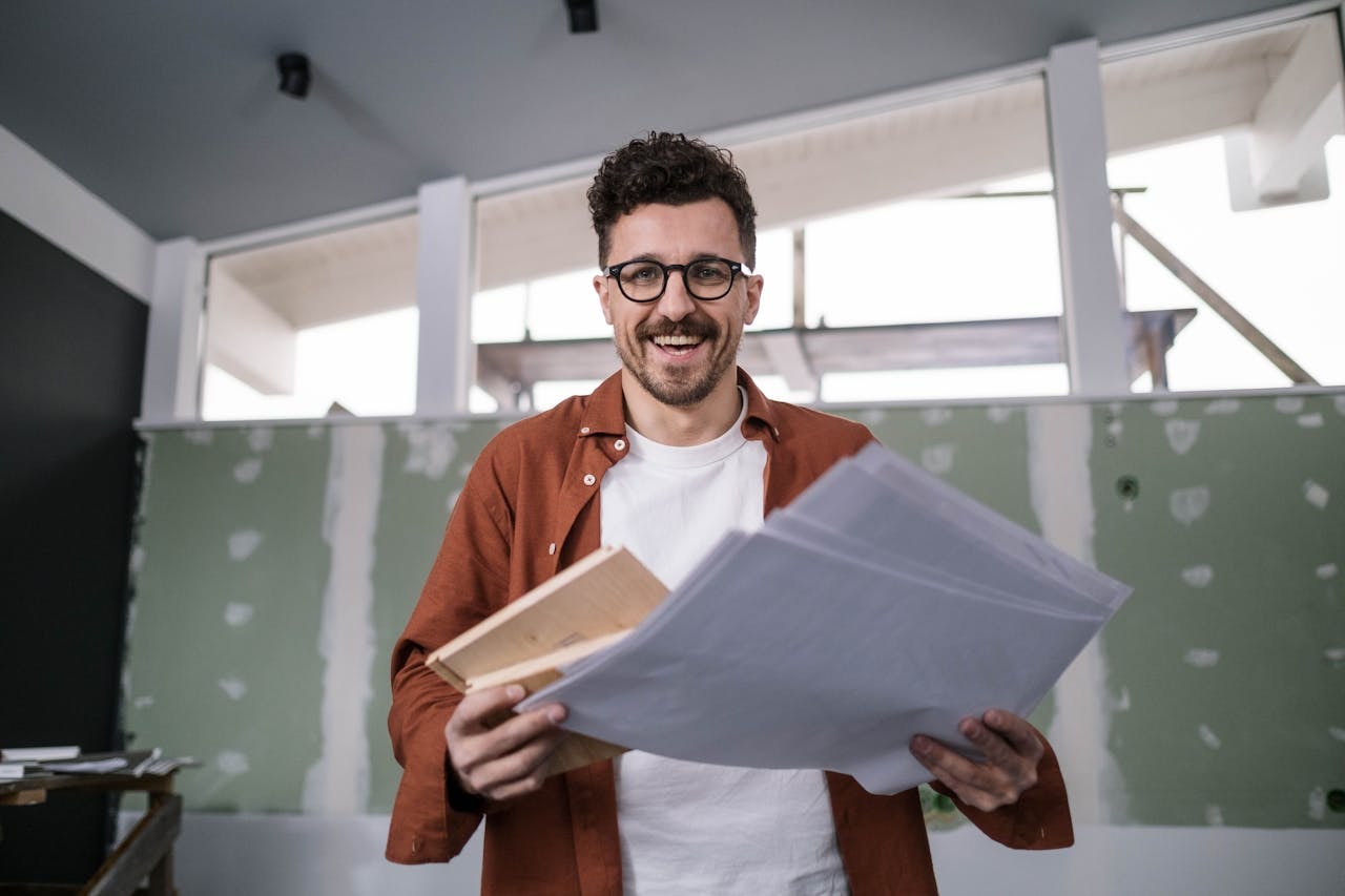 An interior designer holding papers in an empty apartment