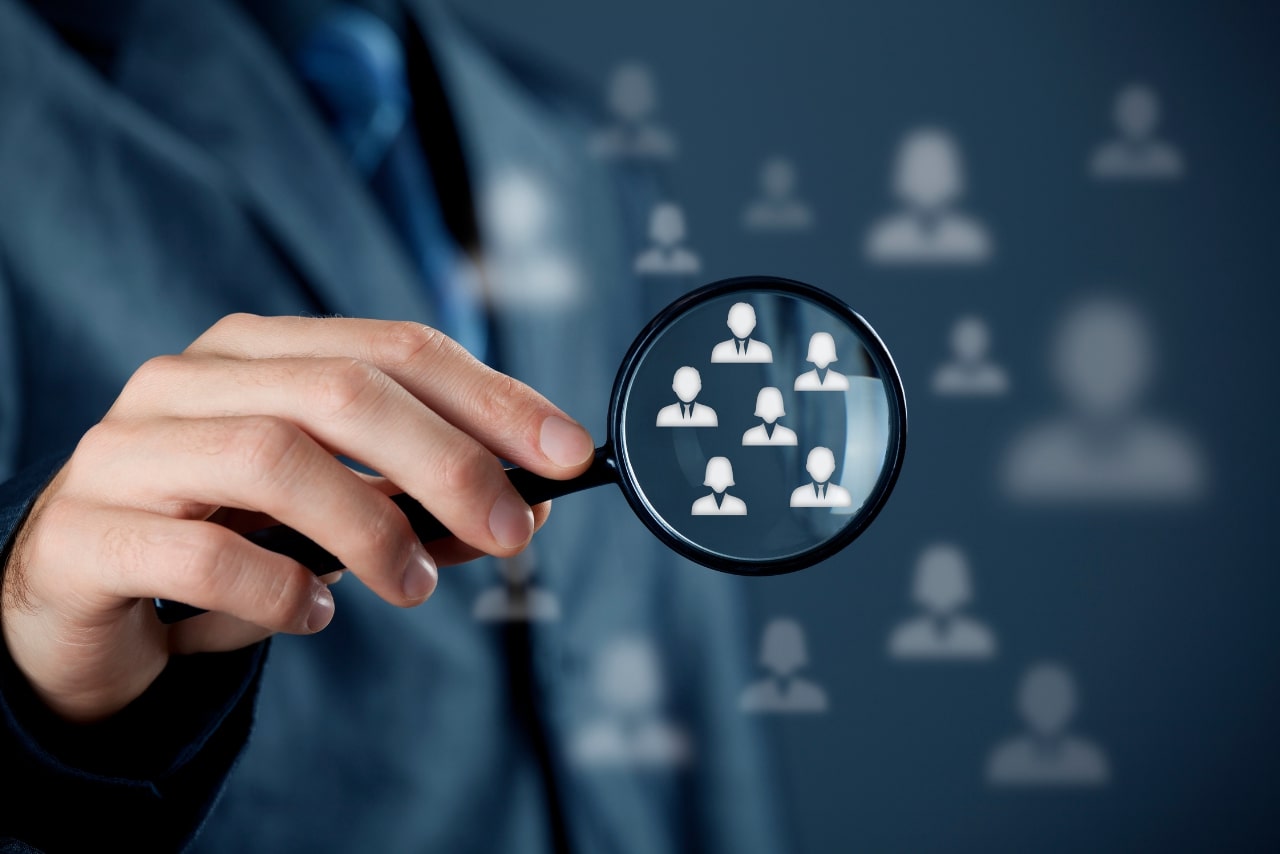 Business person magnifying group of people icons.