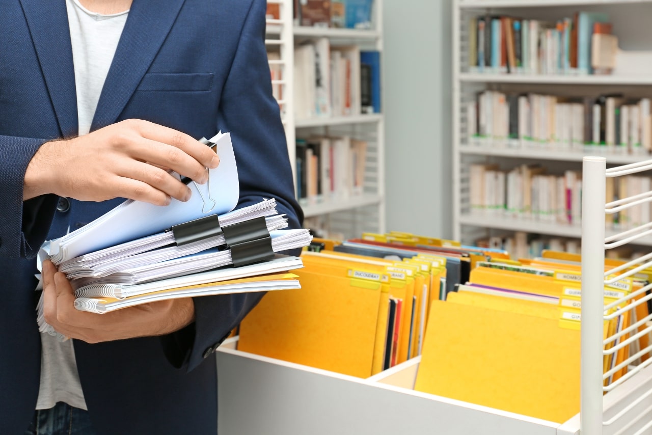 Business person organizing documents with clips and folders.