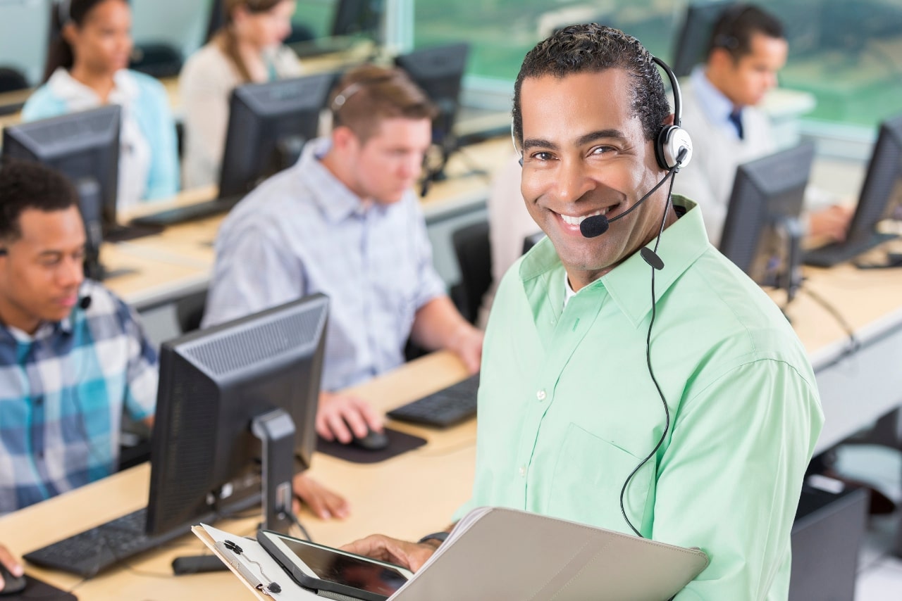Cheerful call center manager holds a customer training manual.