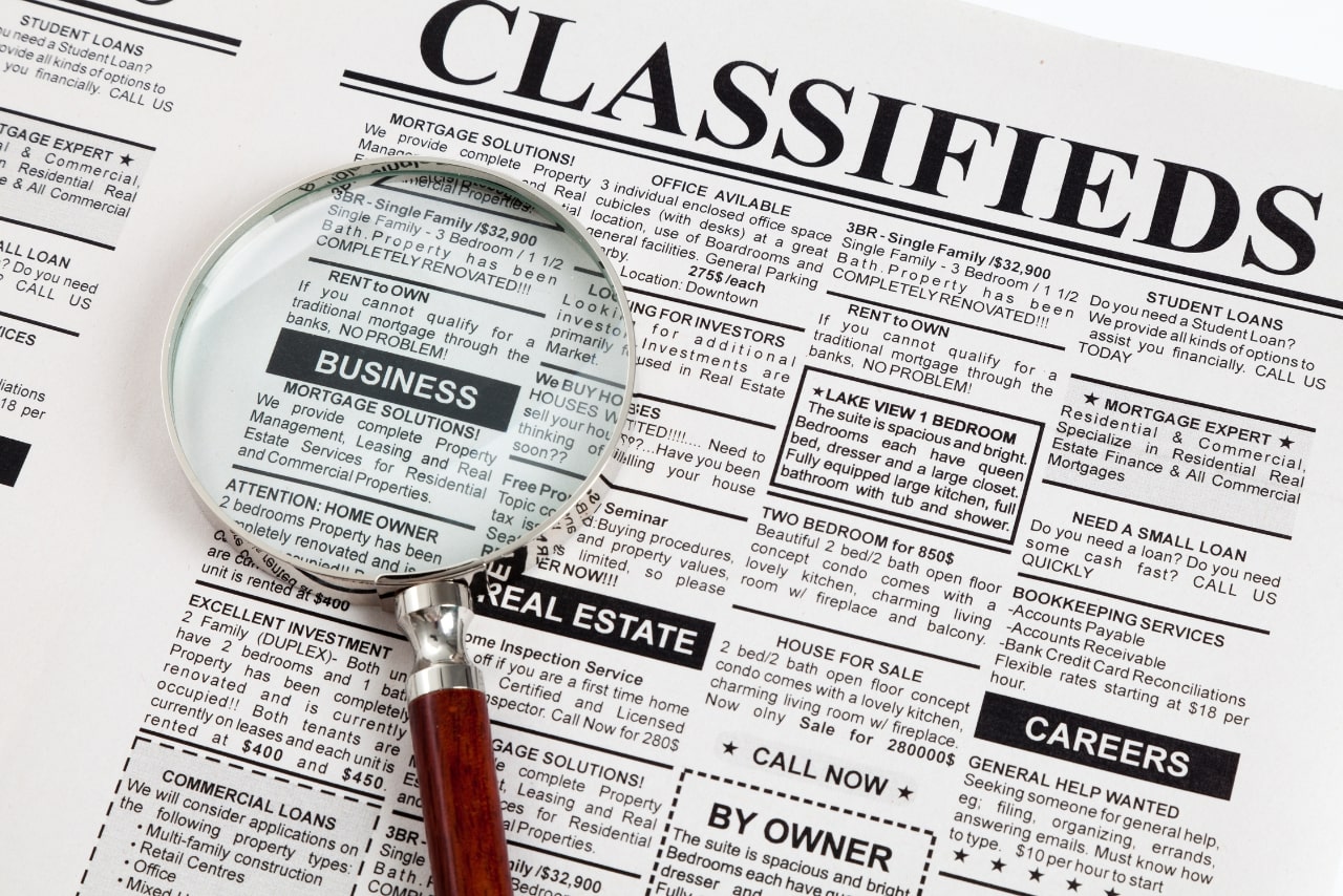 Classified Ad on newspaper magnifying business section.