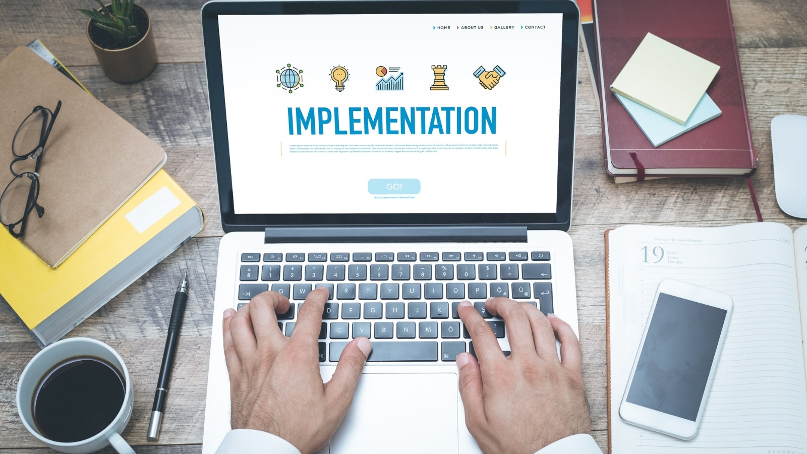 Close up of hands on laptop keyboard with screen showing Implementation word.