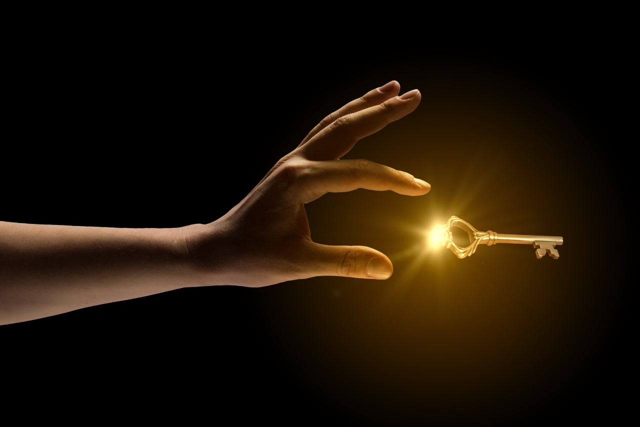 Image of hand catching golden key.