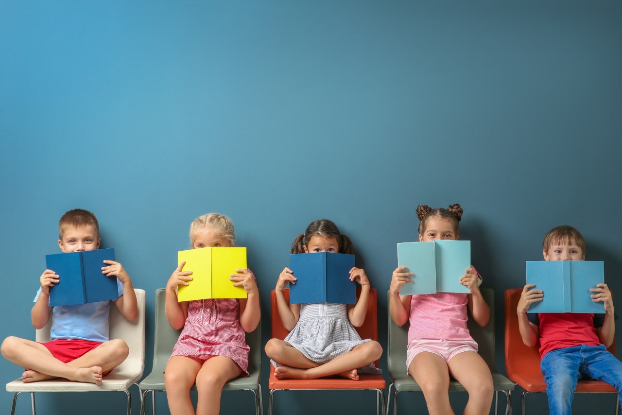 Little children reading books while sitting.
