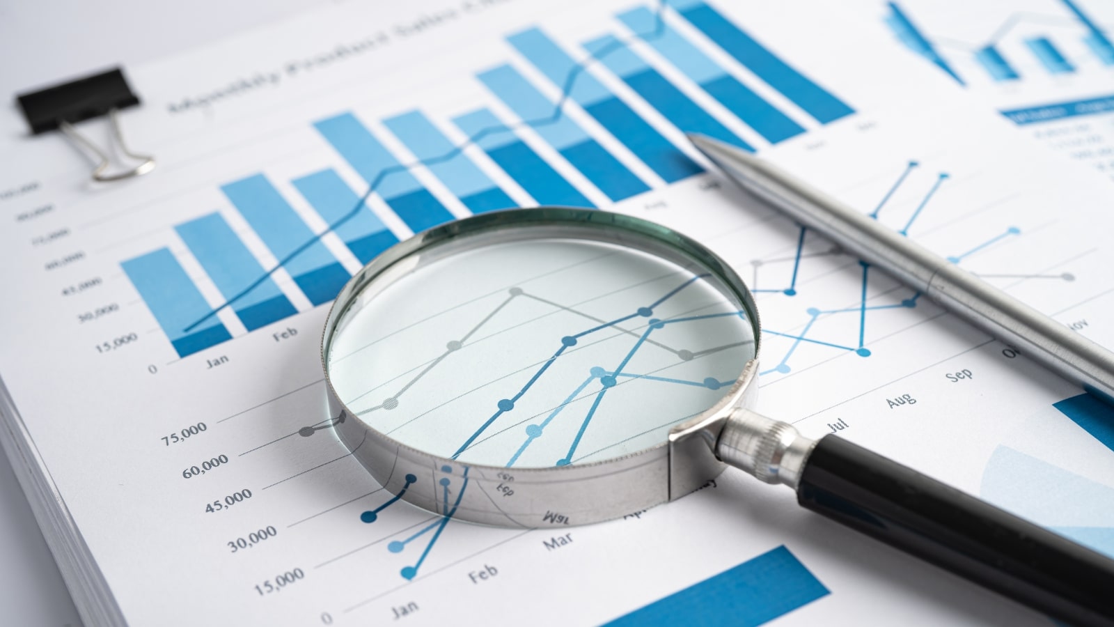 Magnifying Glass on printout of Data Charts, Graphs and metrics.