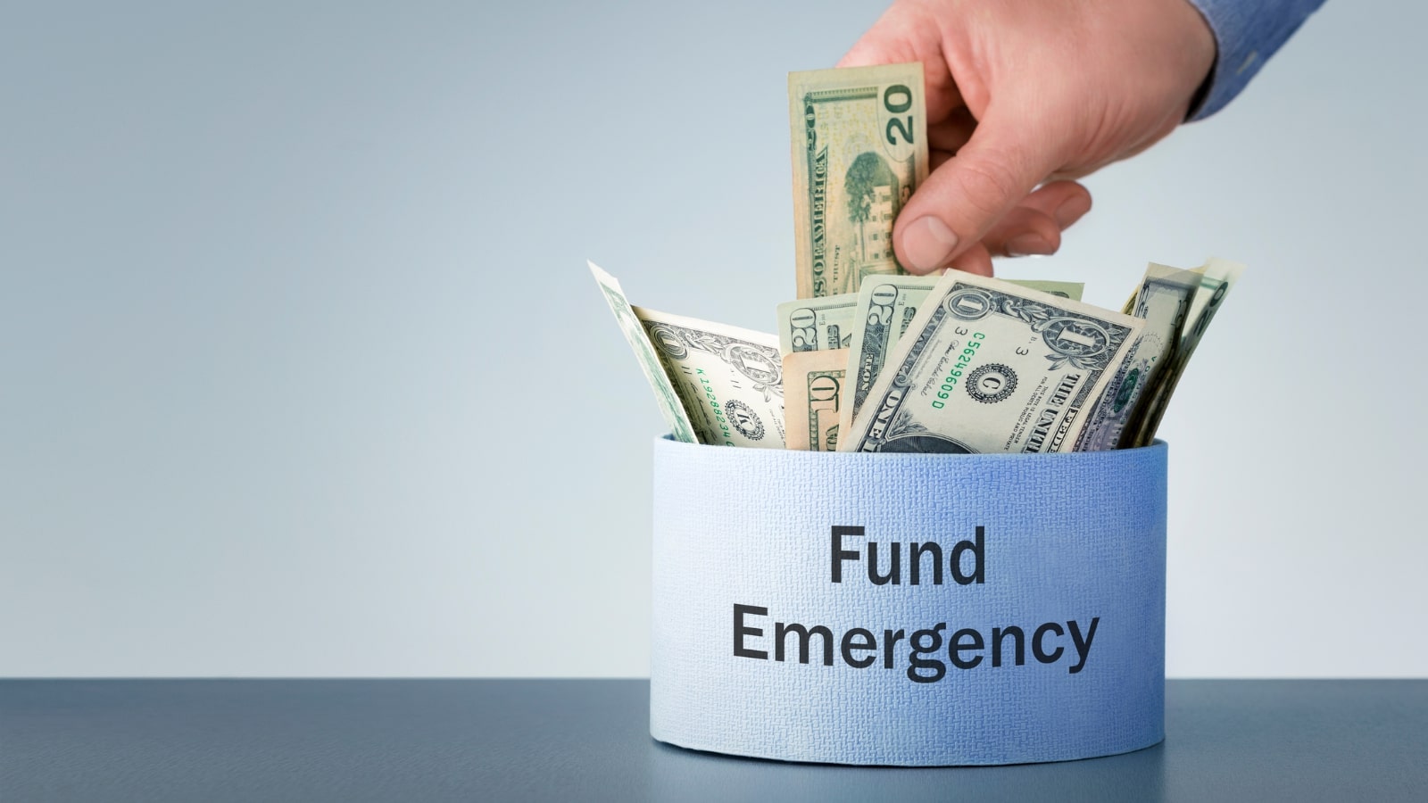 Male hand puts dollars in box with text Fund Emergency.