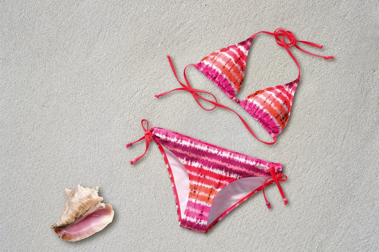 Orange, pink, and white striped bikini on a sandy beach