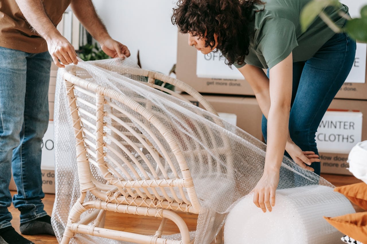 People wrapping a wooden chair in bubble wrap