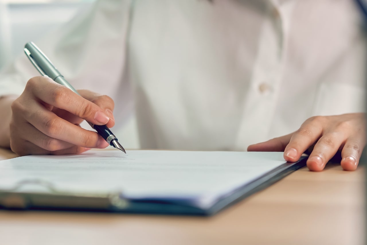 Person filling up form on a clipboard.