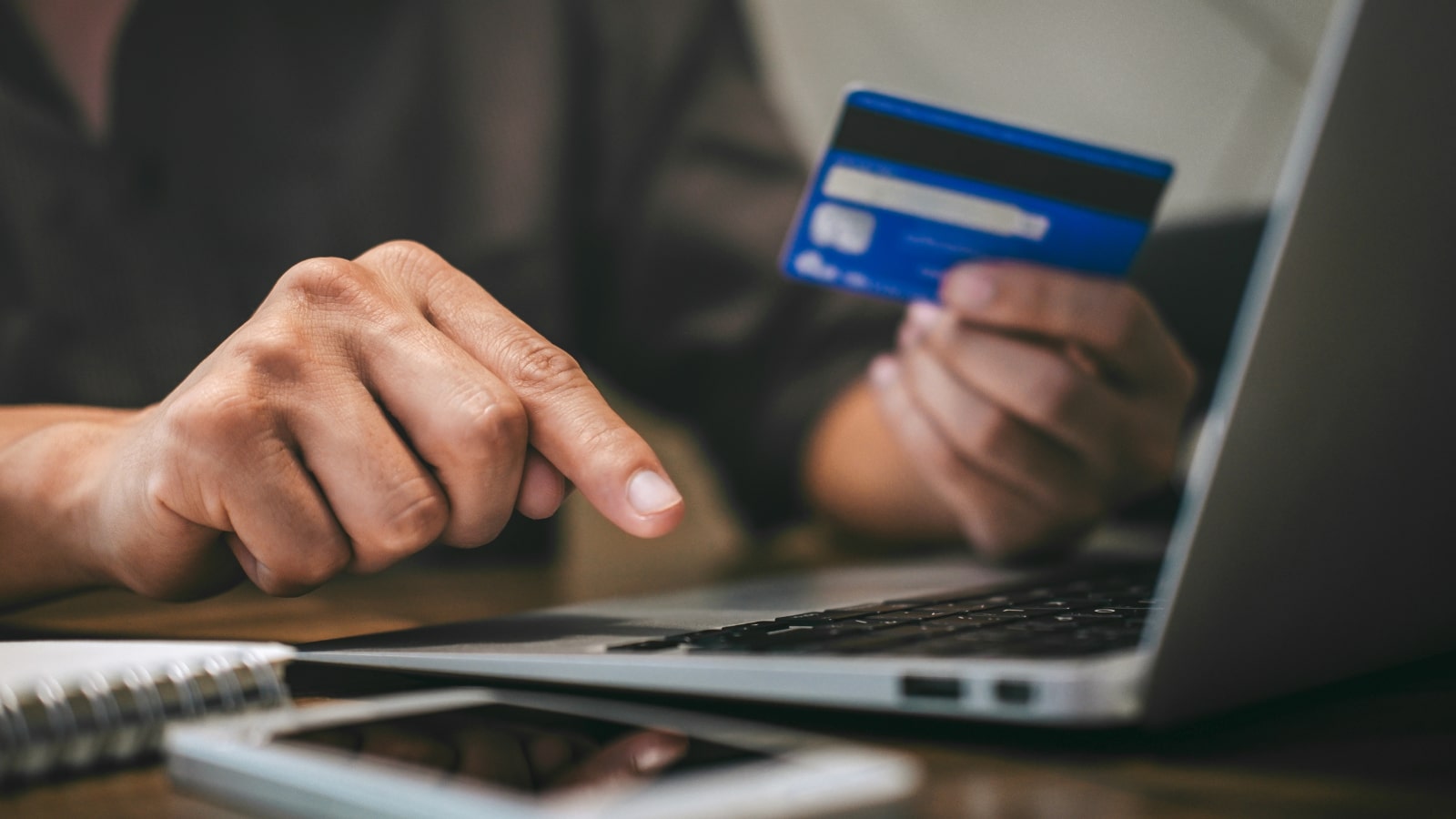 Person typing on laptop while holding creditcard to make online payment.