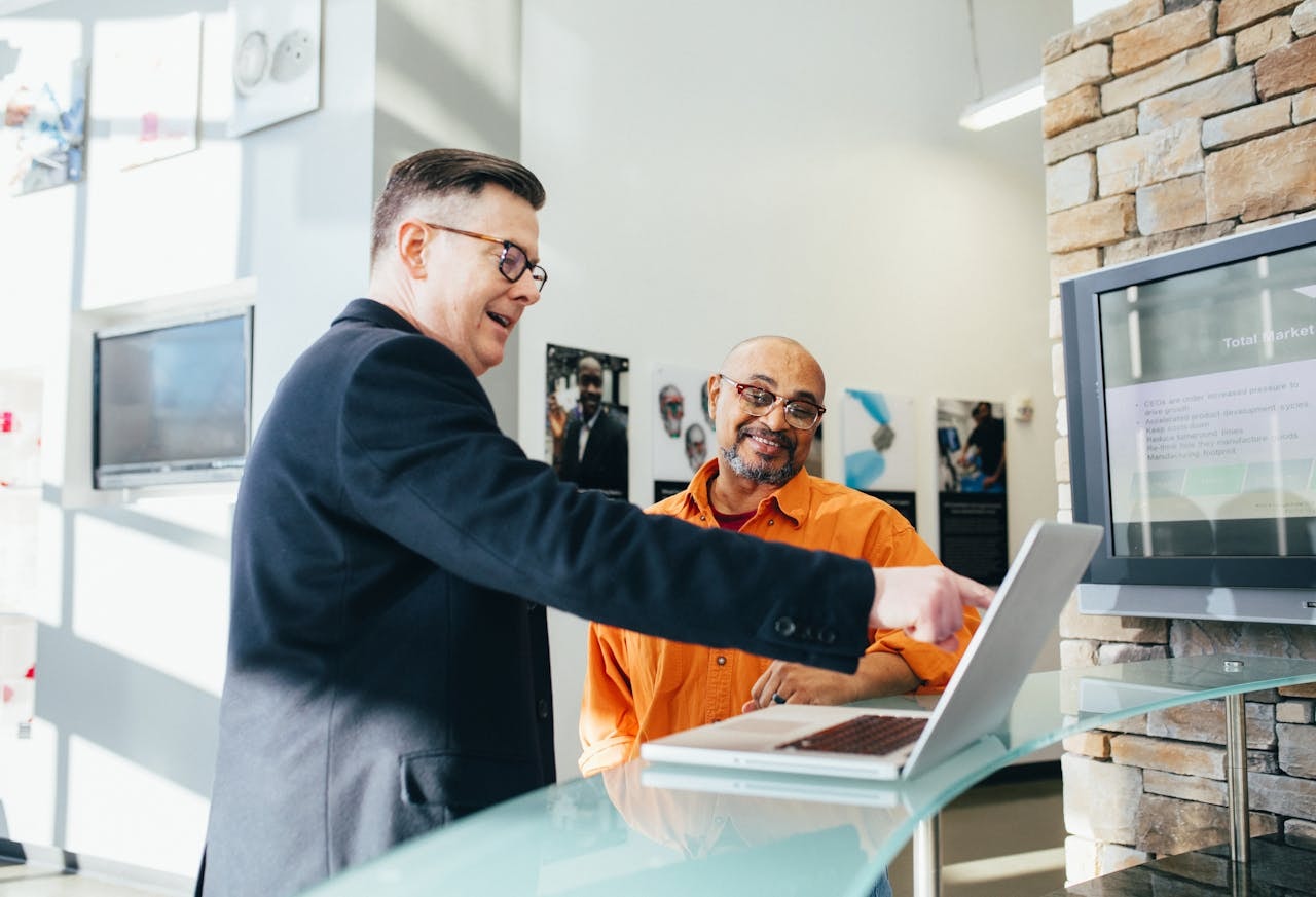 Two men pointing and looking at a laptop