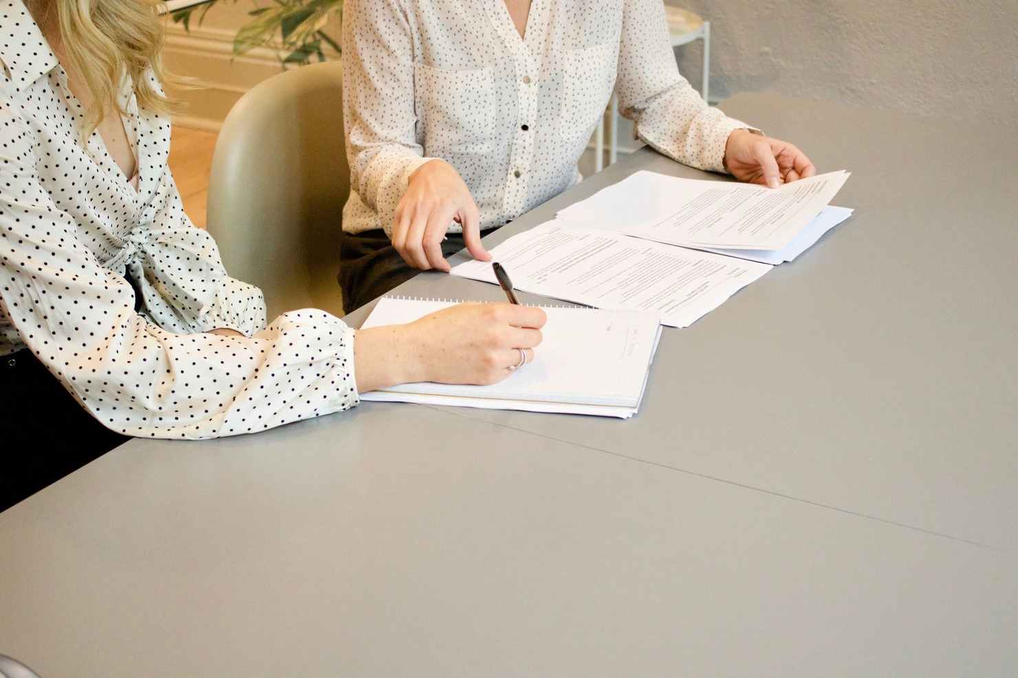 Two women signing legal documents.
