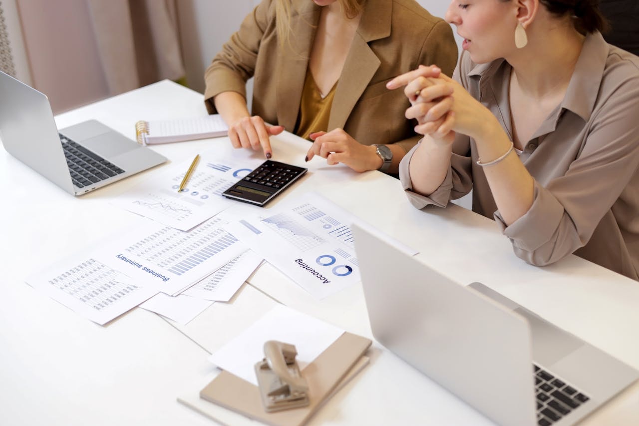 Two women sitting at a desk discussing and doing accounting