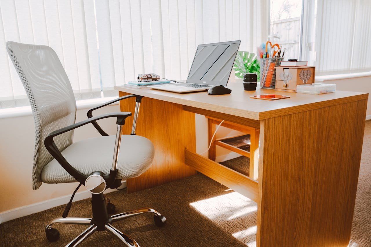 White office chair and brown desk with laptop and office supplies