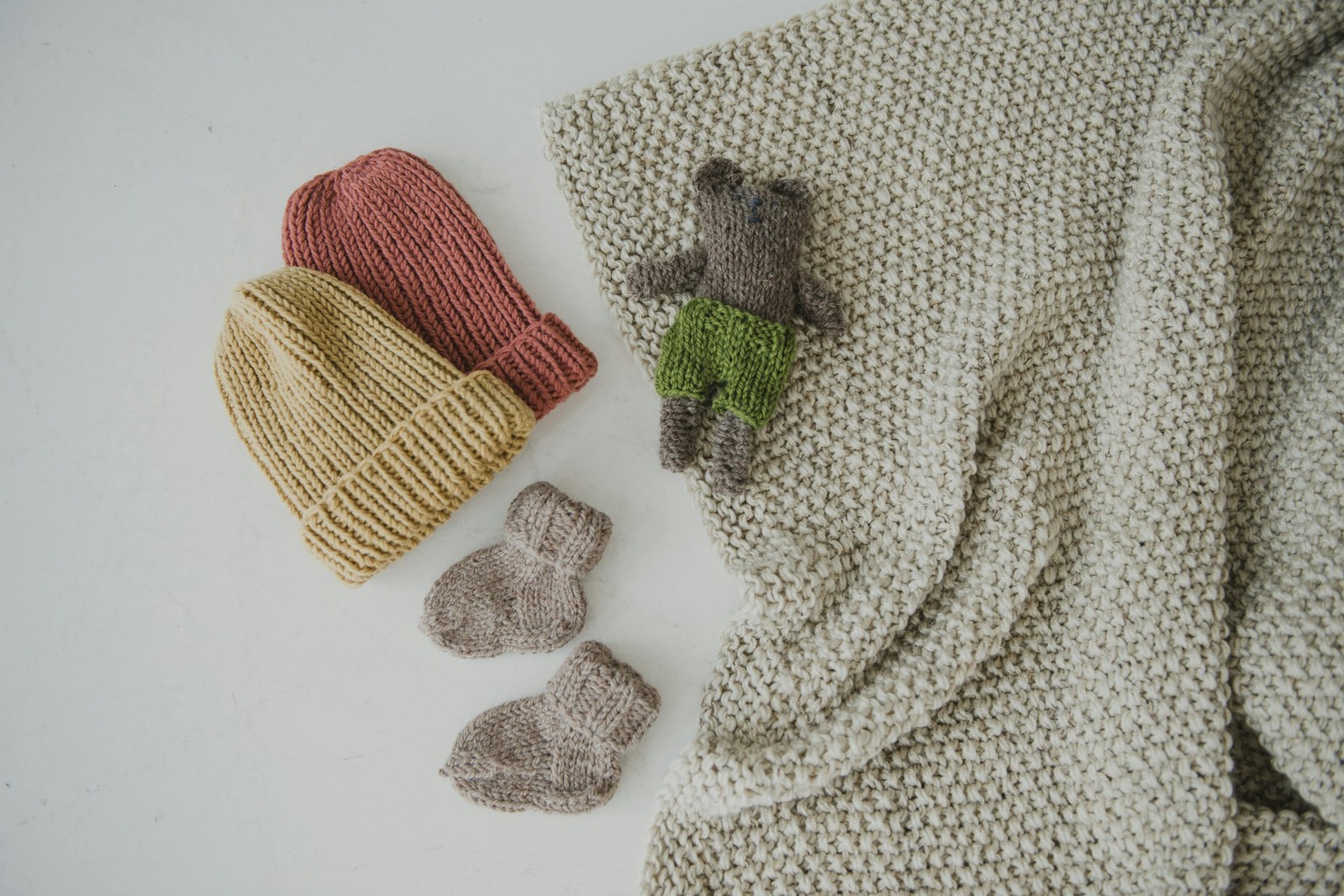 Yellow and Orange Knitted Beanies on White Surface.