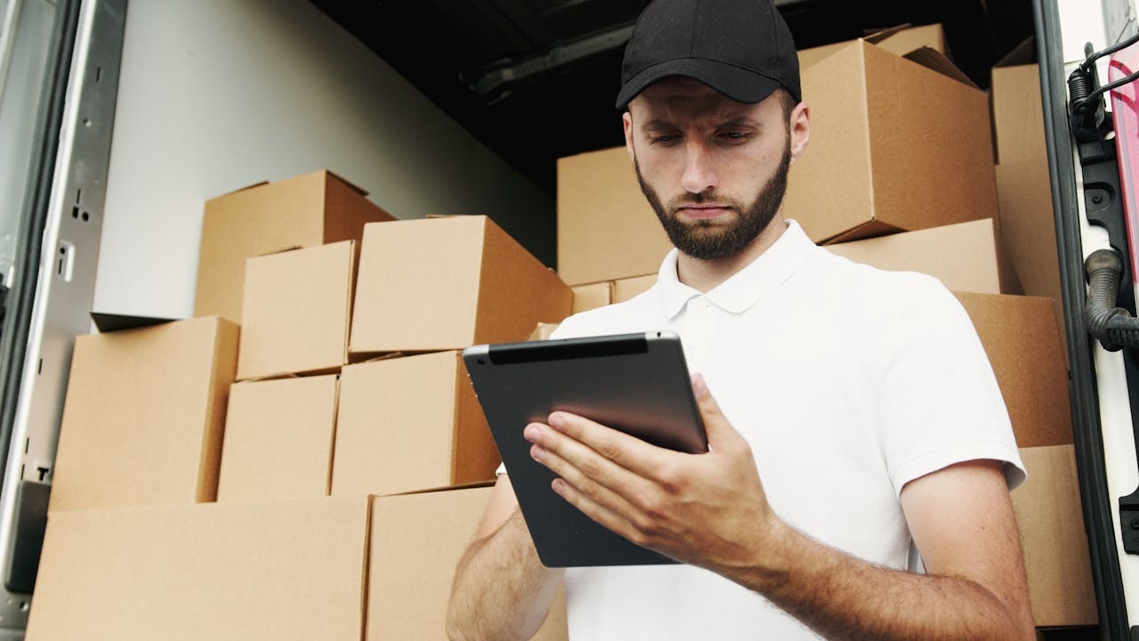 A delivery man looking at a tablet device 