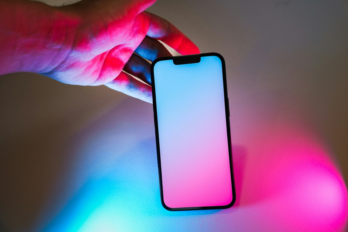 A hand holding a smartphone that displays glowing neon lights
