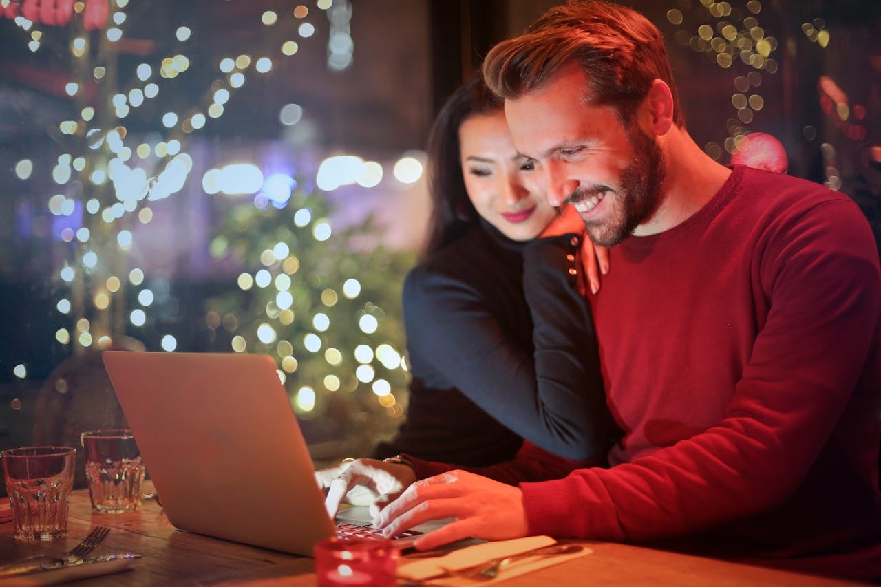 A man and a woman smiling and looking at a laptop