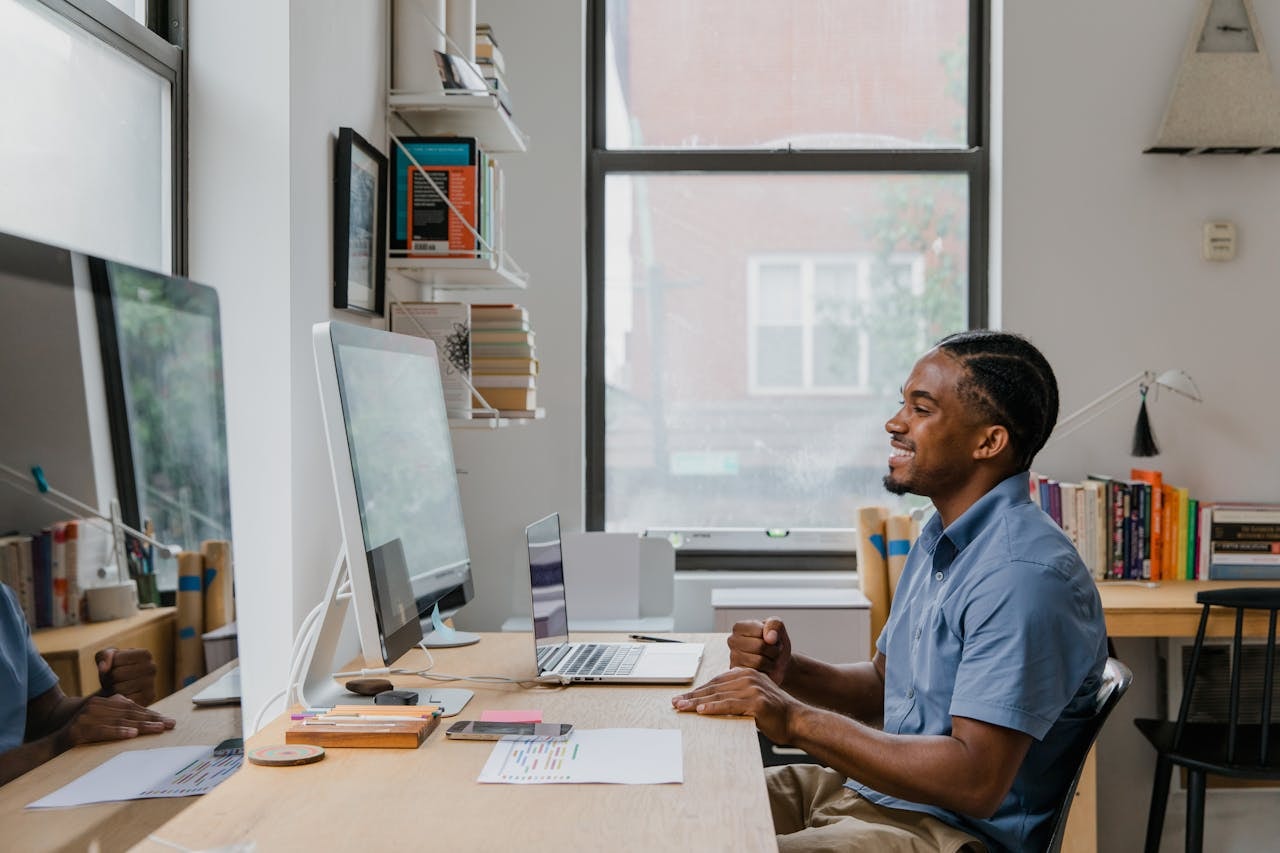 A man looking at a computer monitor and smiling