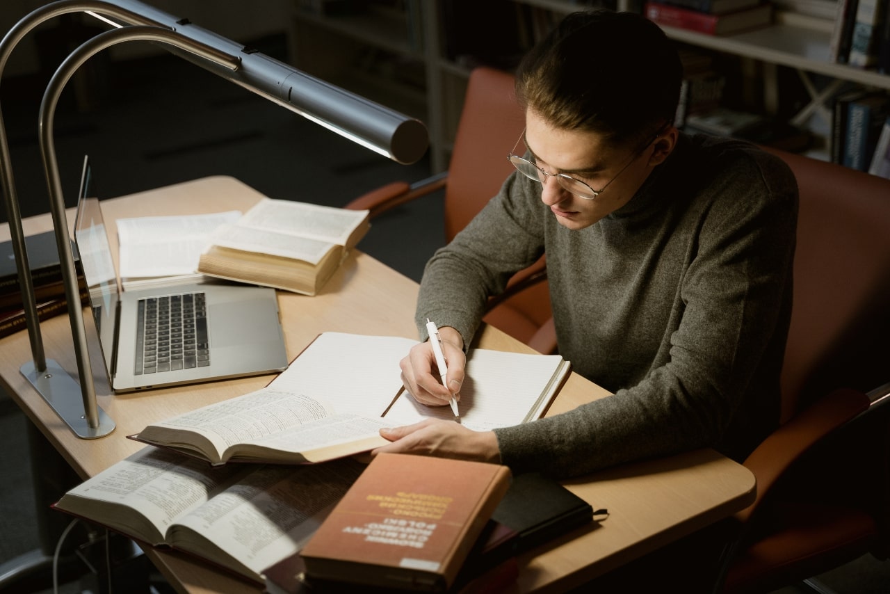 A man taking notes while reading a book.