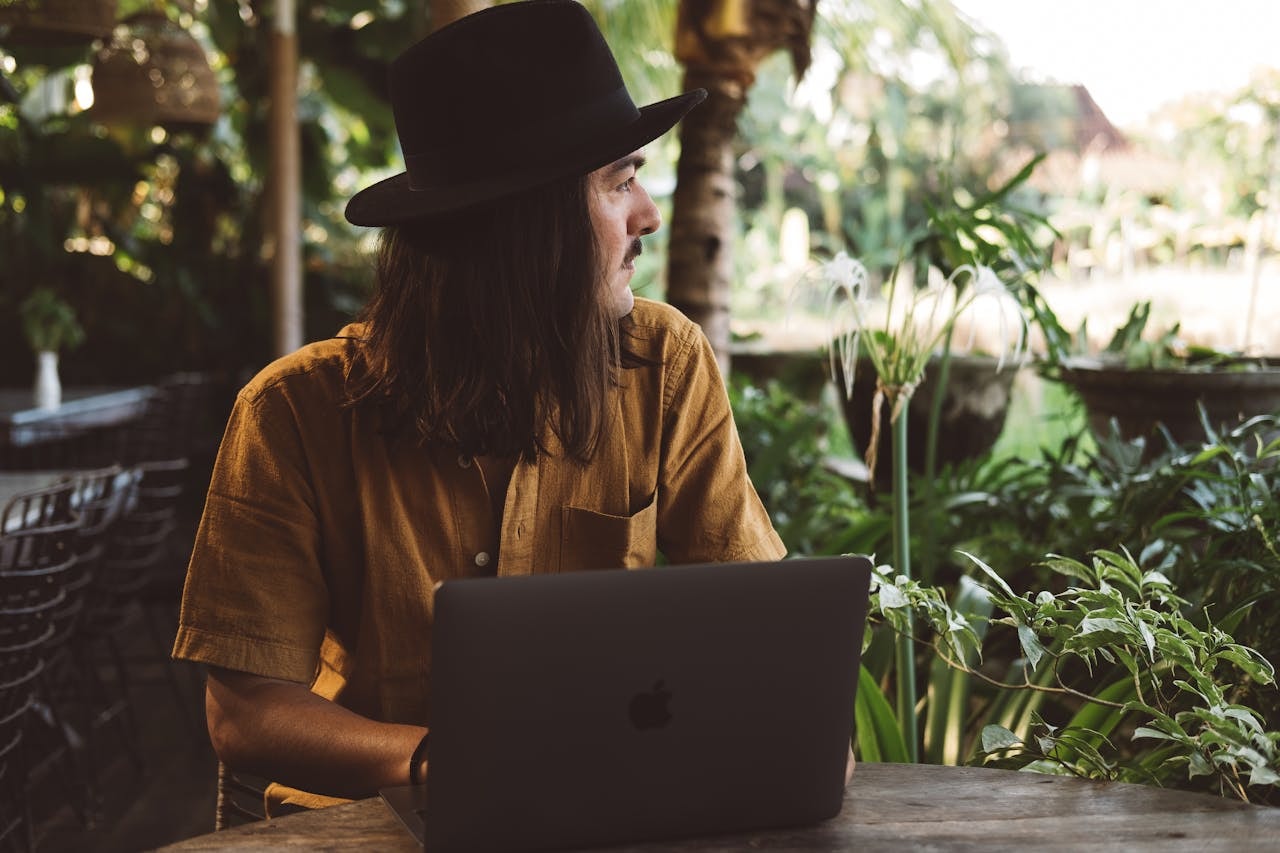 A man with a laptop open and looking at plants