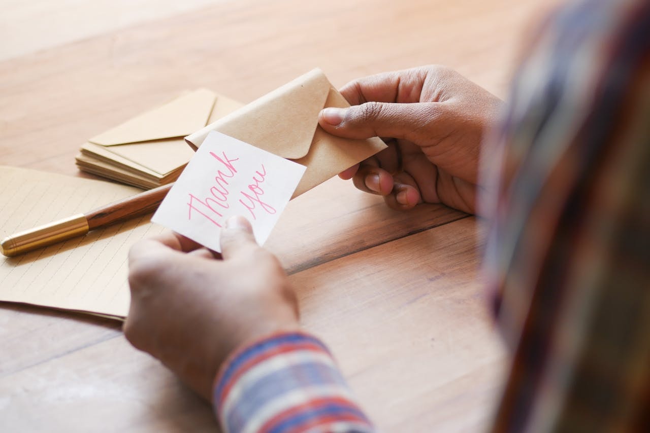 A person holding a thank you note and an envelope
