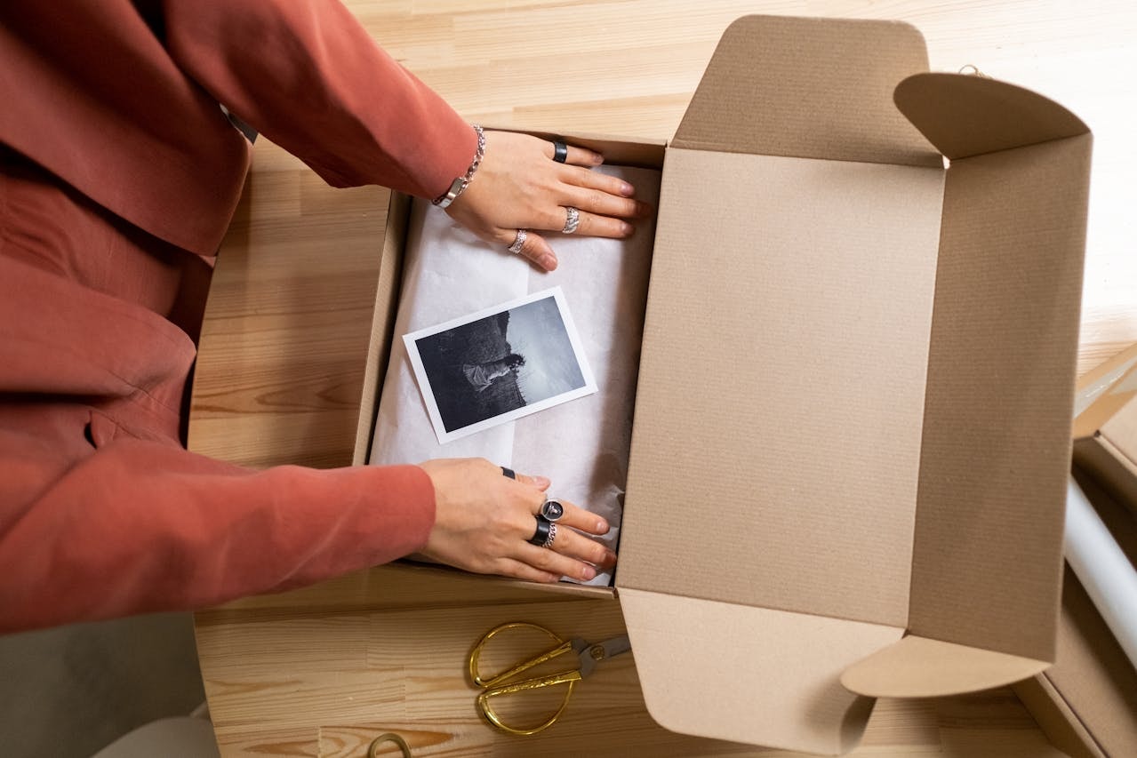 A person packing items into a cardboard box