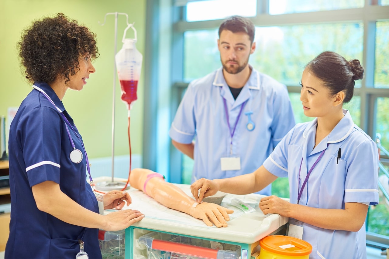 A senior nurse talking to two student nurses.