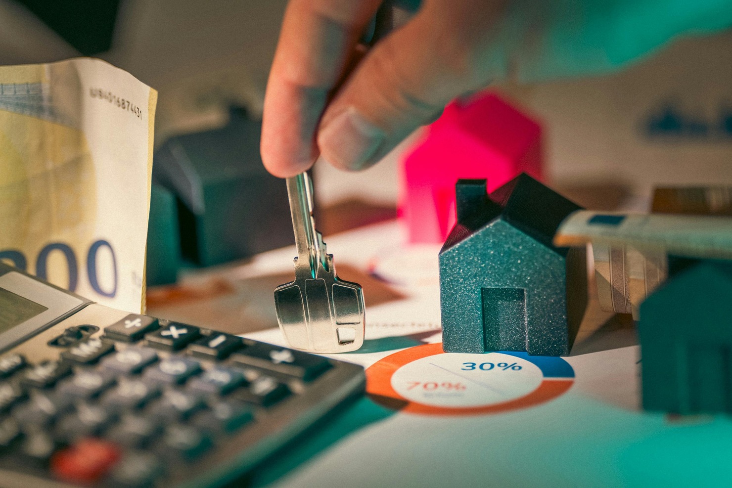A small house with a hand holding a key, symbolizing real estate investment.