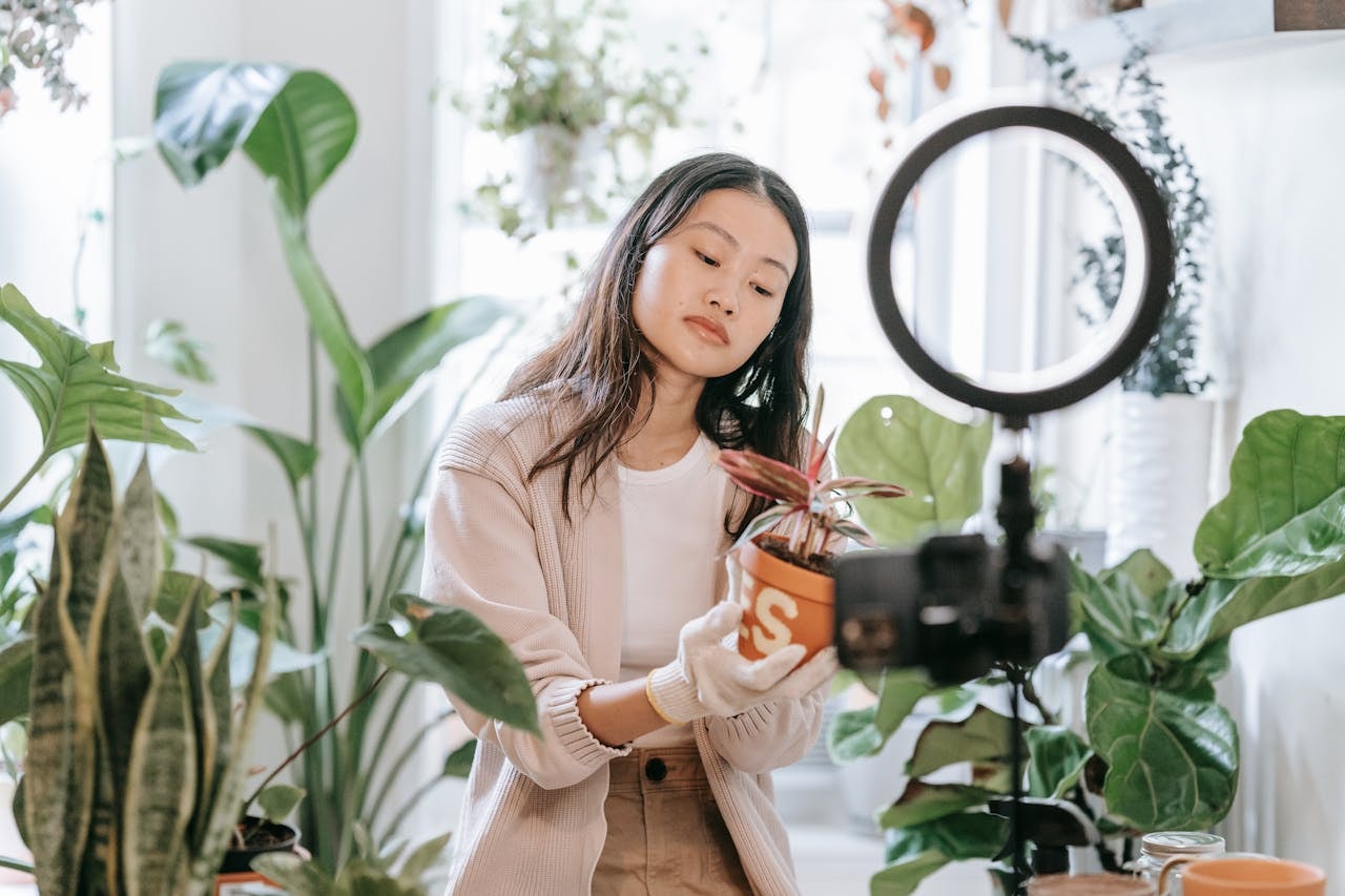 A woman holding a potted plant and recording a video