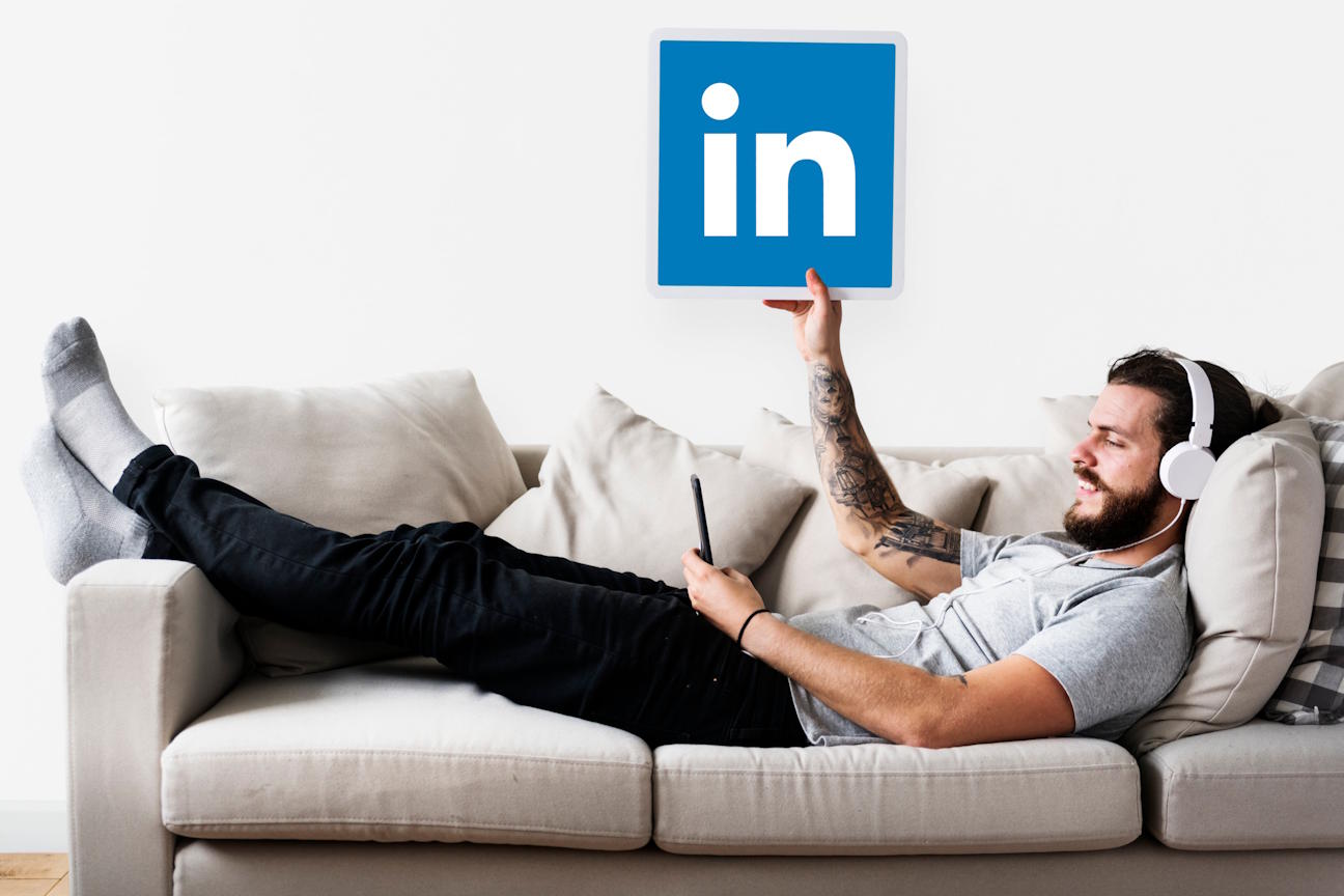 Person lying on couch while raising Linkedin's logo.