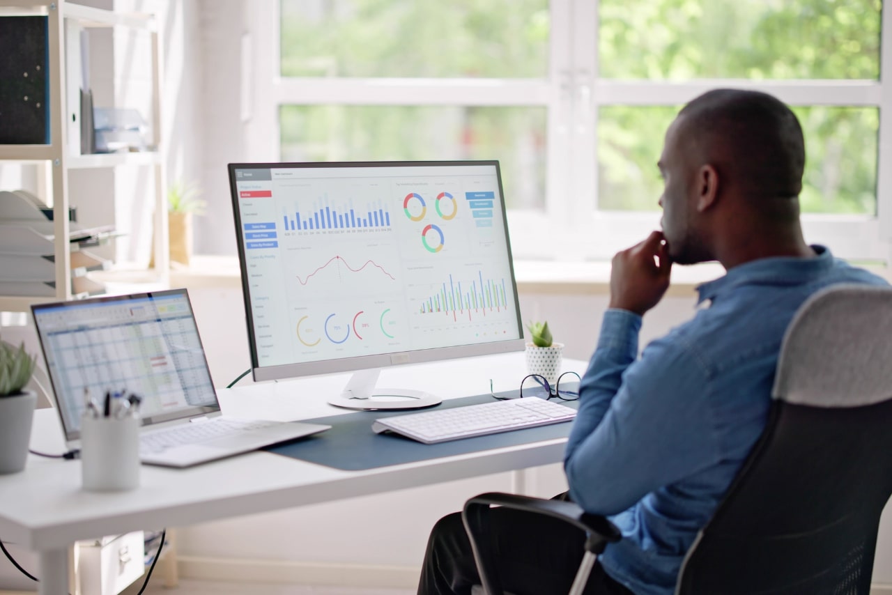 Business owner focusing on dekstop computer screen showing metrics and analytical tools on computer.