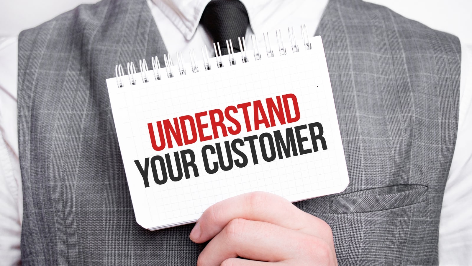 Businessman with notebook with text UNDERSTAND YOUR CUSTOMER.